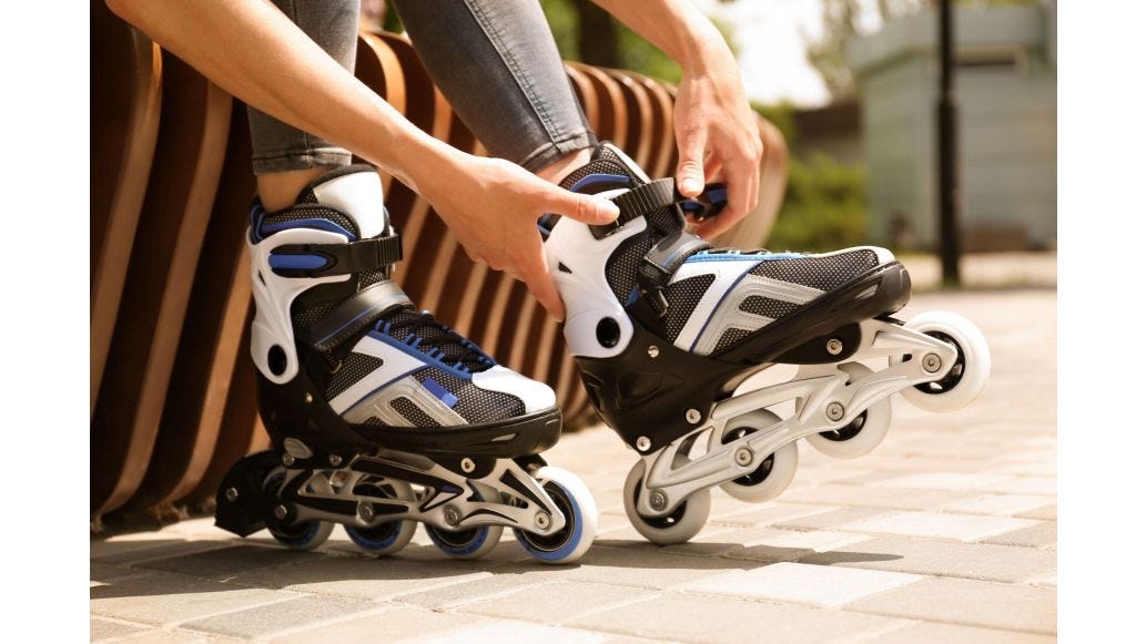 Person strapping up their white and black roller blades
